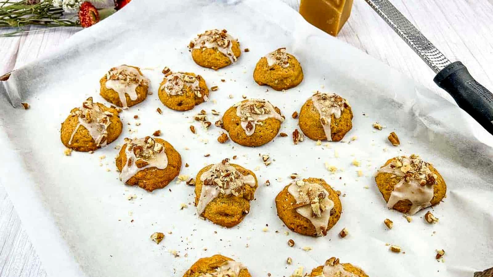 Sweet Potato Cookies on a baking sheet with icing and nuts.
