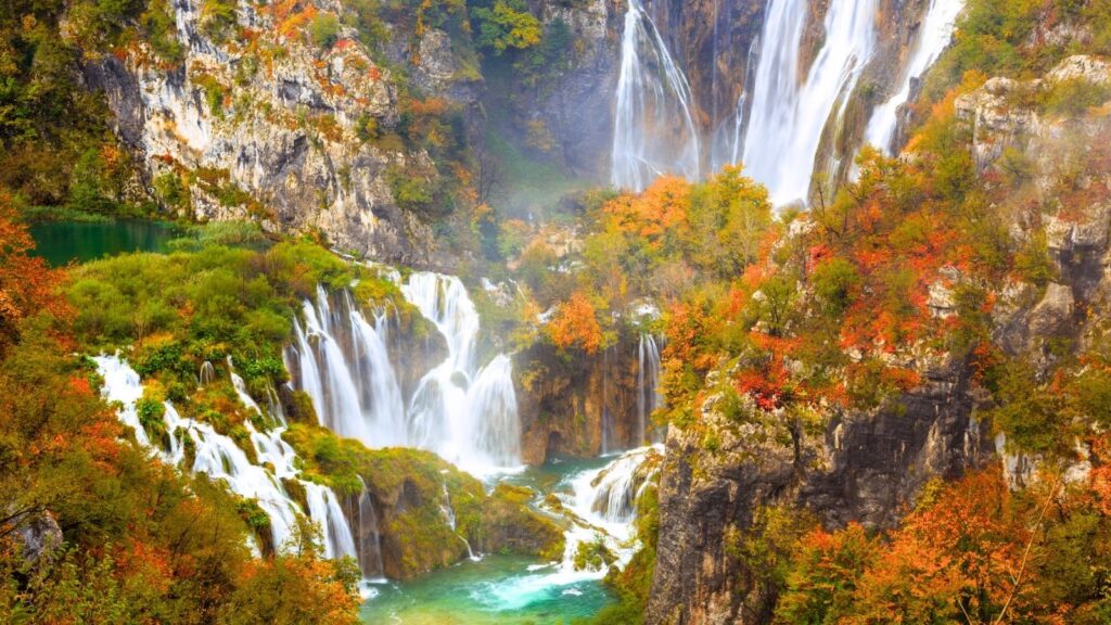 Beautiful waterfall surrounded by colorful fall foliage in a lush forest.