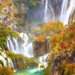 Beautiful waterfall surrounded by colorful fall foliage in a lush forest.