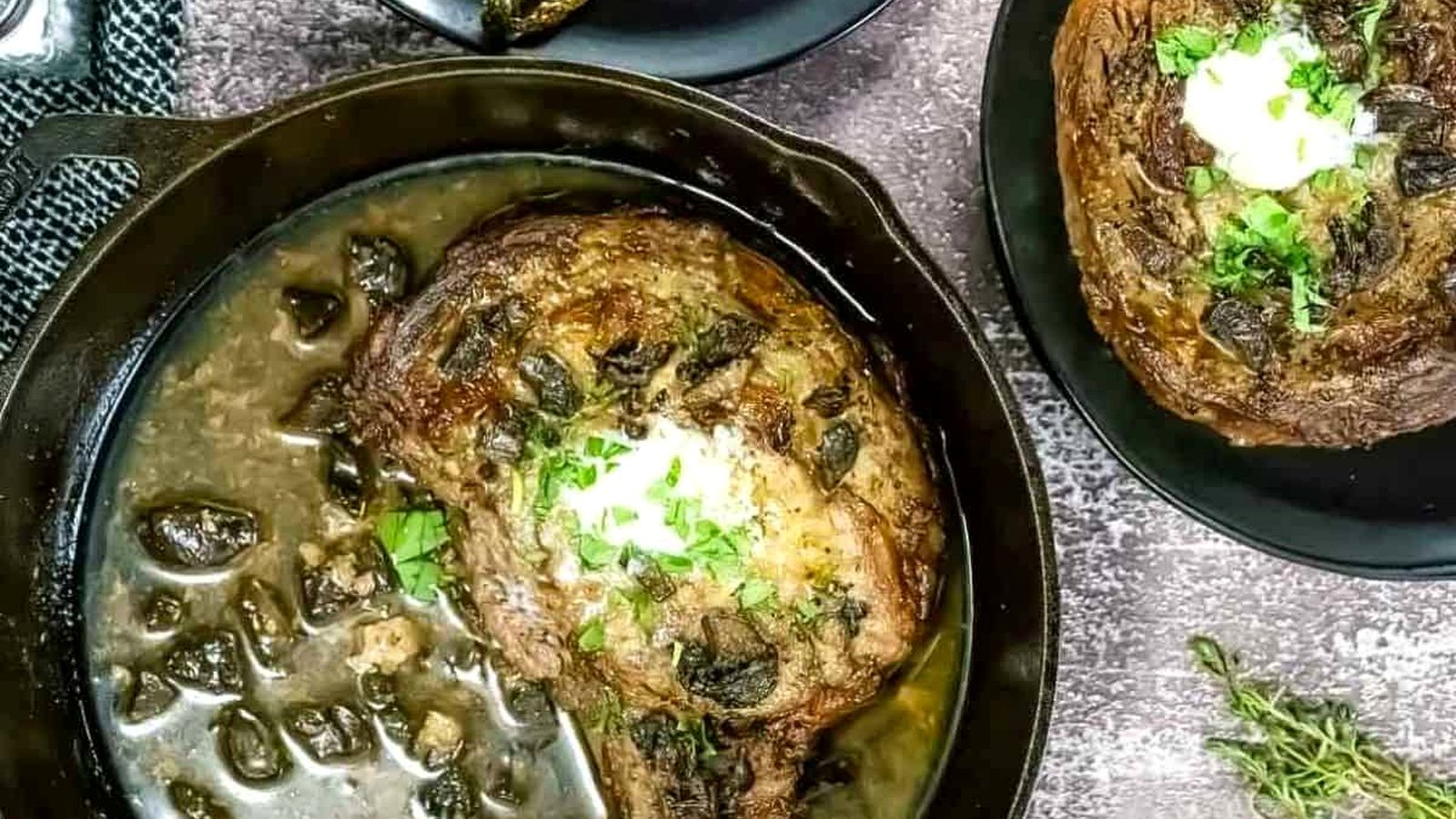 A Broiled Prime Rib & Roasted Asparagus, and a dollop of sauce in a cast-iron skillet with mushrooms, next to a plate of steak and roasted asparagus.