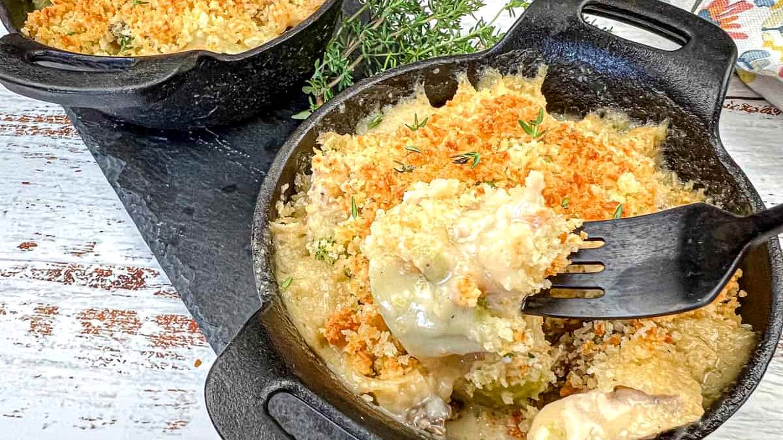 Two cast-iron skillets filled with vintage chicken divan and a fork dishing up one serving.