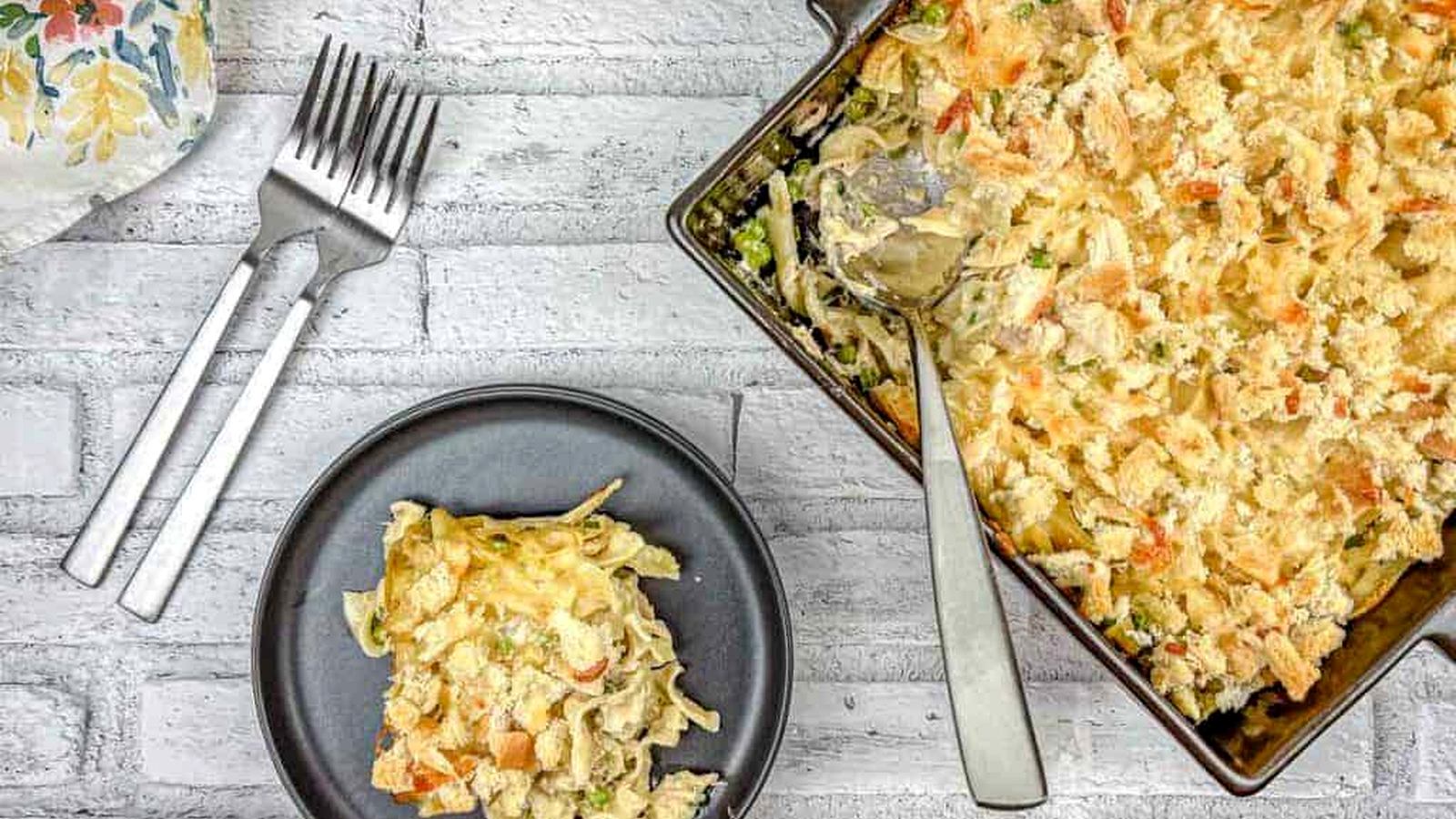 Top-down shot of Tuna Noodle Casserole on a dish with a small portion on a black plate.