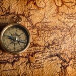 A vintage compass rests on an old, detailed treasure map with a large red X marking a location, evoking the excitement of a Grand Forks treasure hunt.