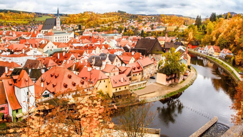 Scenic view of a European town with colorful autumn foliage and a river.
