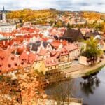 Scenic view of a European town with colorful autumn foliage and a river.