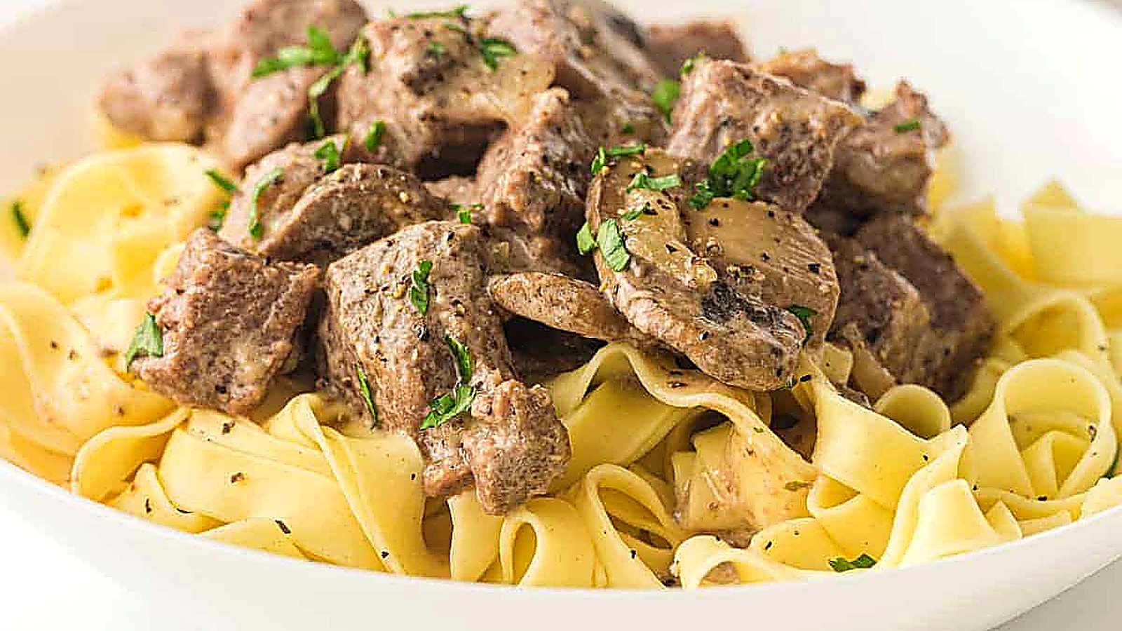 A plate of Slow Cooker Beef Stroganoff garnished with chopped parsley.