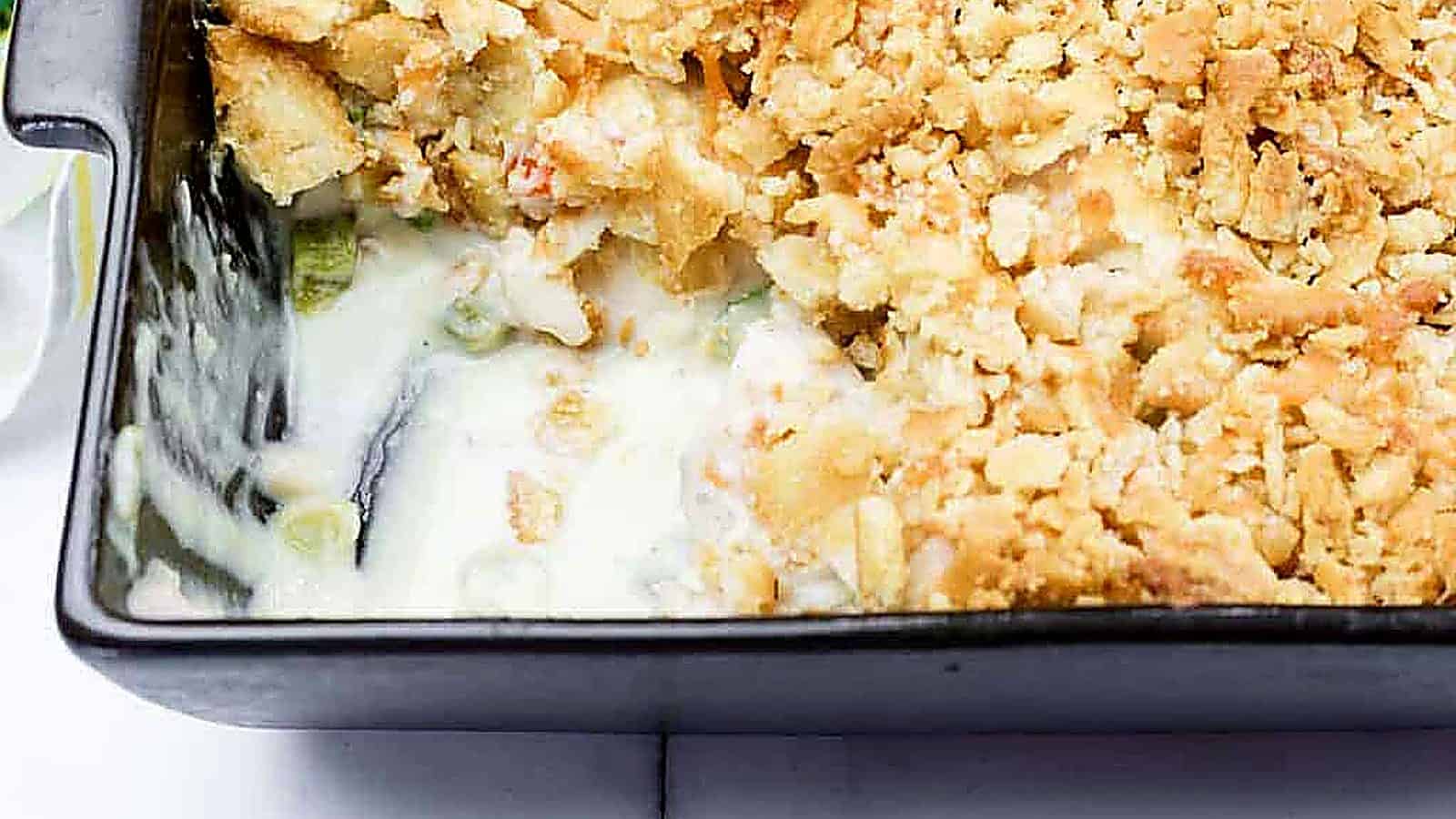 A close-up of a Cheesy Ritz Cracker Chicken Casserole dish with a portion missing from one side.