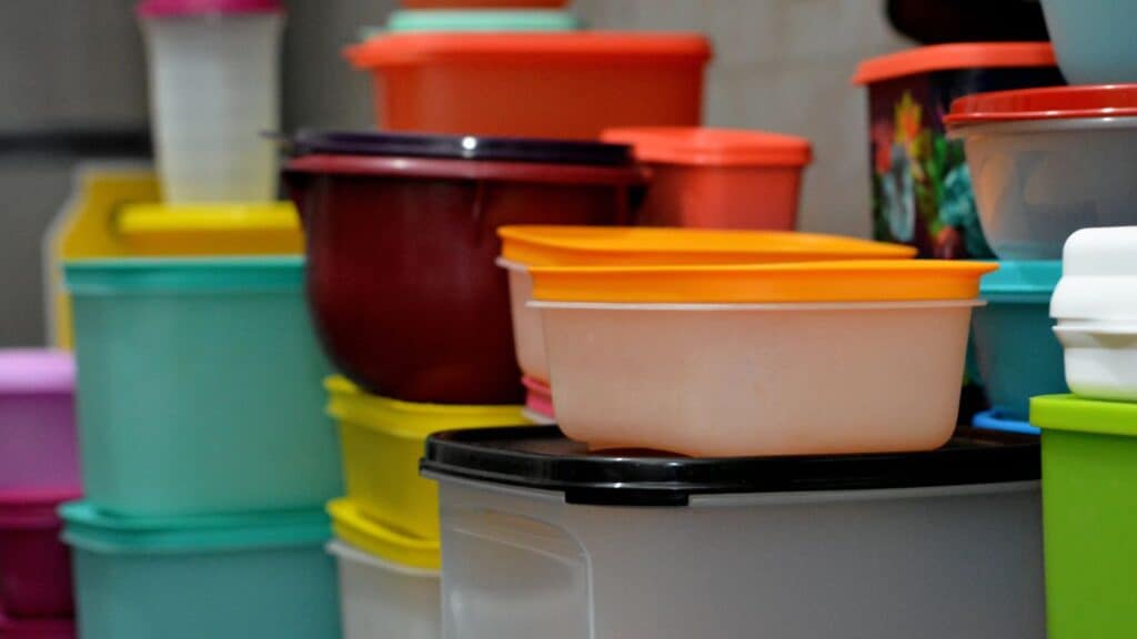 A stack of assorted plastic food containers with different colored lids, arranged closely together&mdash;a classic piece of kitchen gear Americans remember from family gatherings and everyday meals.