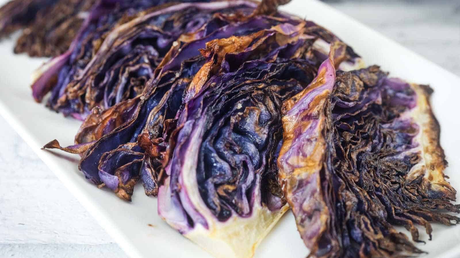 Slices of roasted red cabbage arranged on a white rectangular plate.