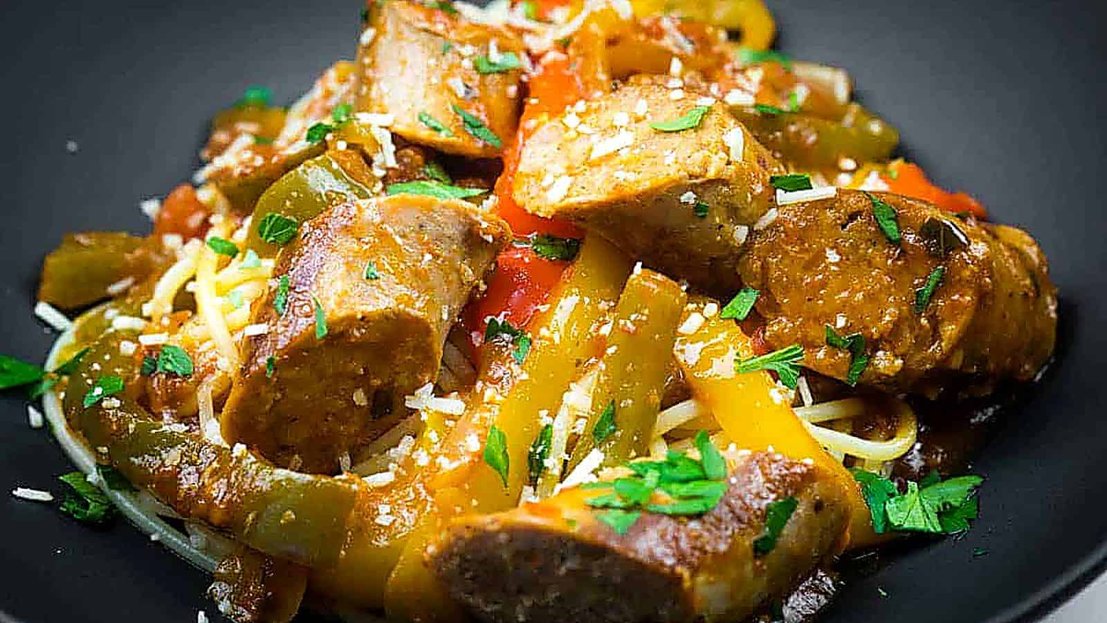 Slow cooker sausage and peppers garnished with grated cheese and chopped parsley.