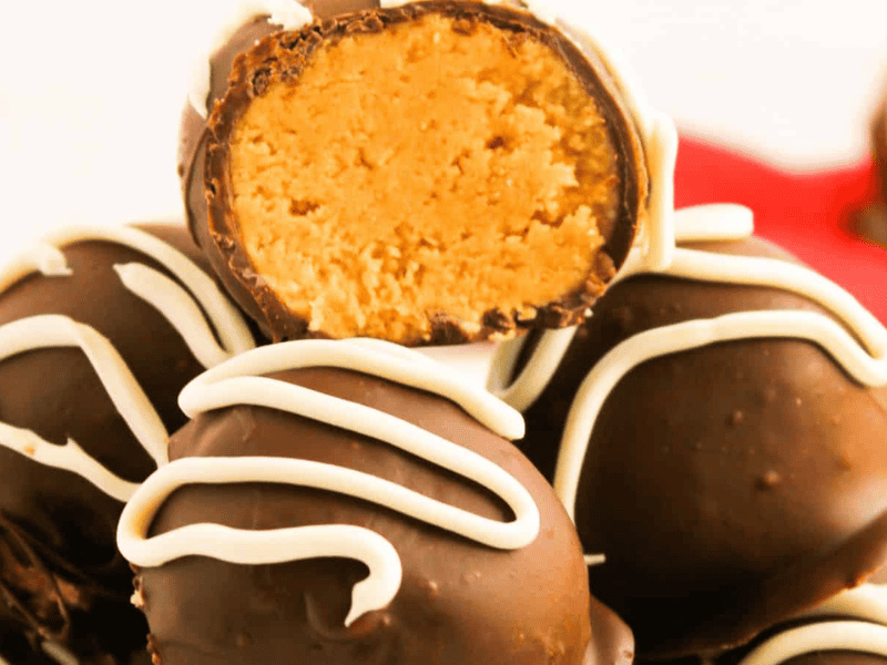 A stack of chocolate truffles with white icing, one cut open to reveal a peanut butter filling.