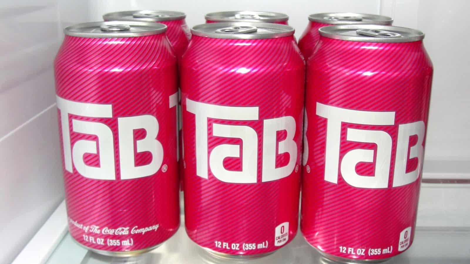 Six pink cans of Tab soda, each 12 fl oz (355 ml), are arranged in two rows inside a refrigerator—a nostalgic nod to sodas that had their moment.