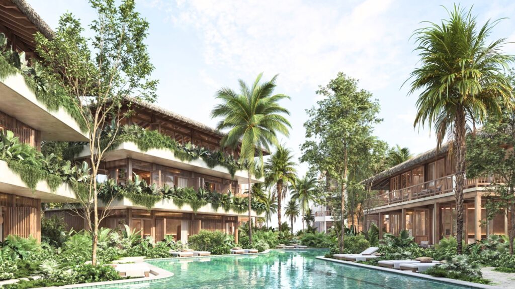 A tropical resort features two-story buildings with balconies, lush greenery, palm trees, and a central pool surrounded by lounge chairs under a partly cloudy sky.