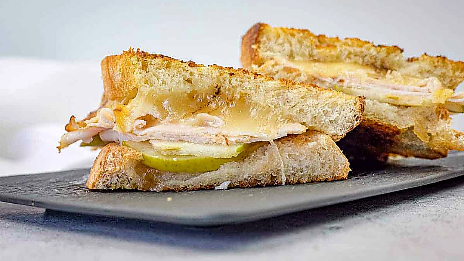 A close-up of a sliced Turkey & Apple Grilled Cheese on a plate.