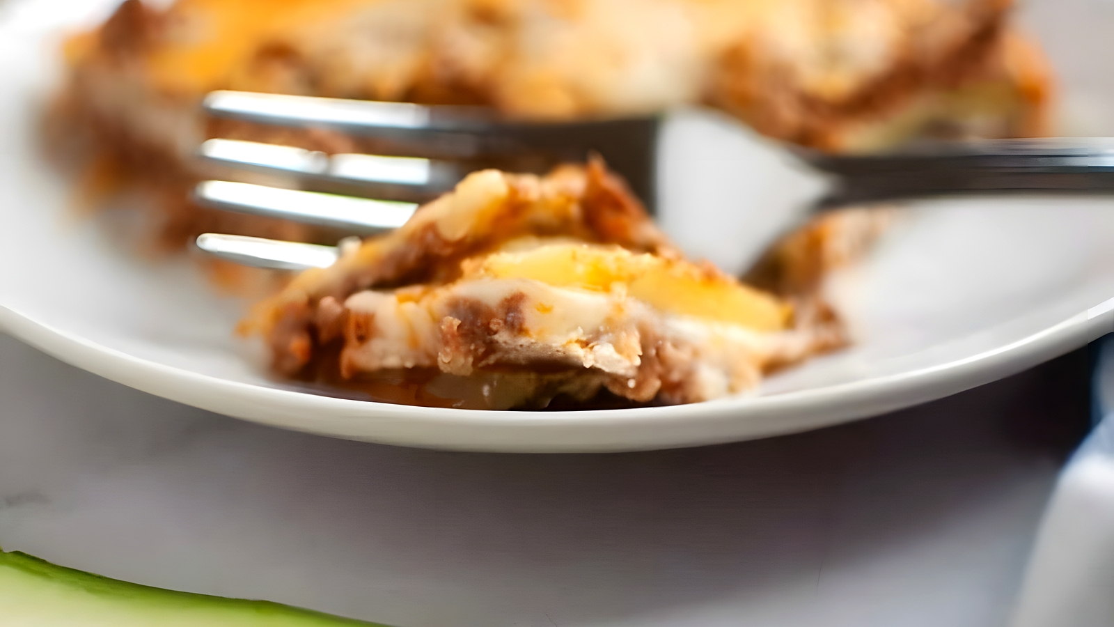 A close-up, slightly high-angle view of Zucchini Lasagna squares arranged on a dark gray baking sheet, each topped with a glossy, light brown apple filling and a generous sprinkle of light brown crumb topping.