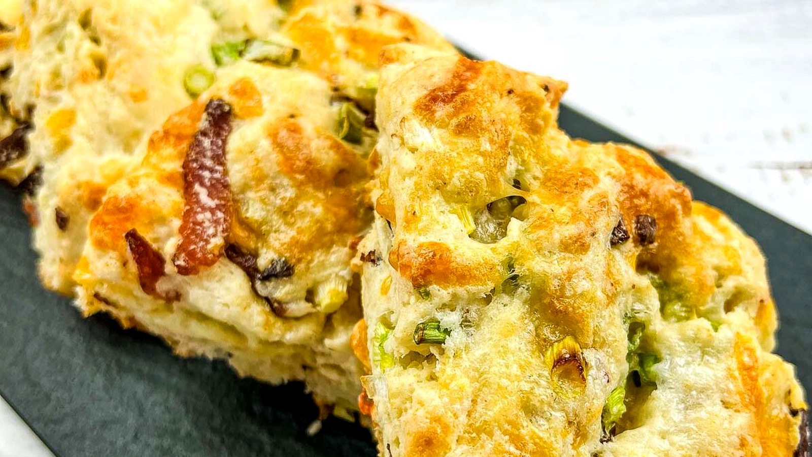 Bacon, Cheddar, Green Onion Scones on a black plate.