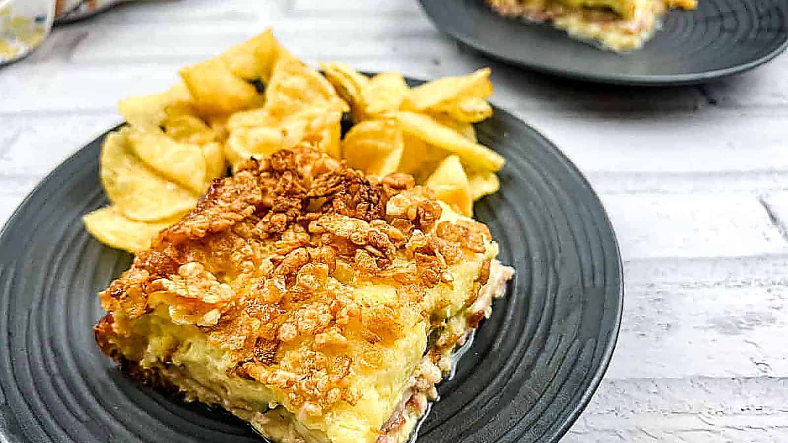 A piece of Cuban sandwich casserole on a plate with potato chips.