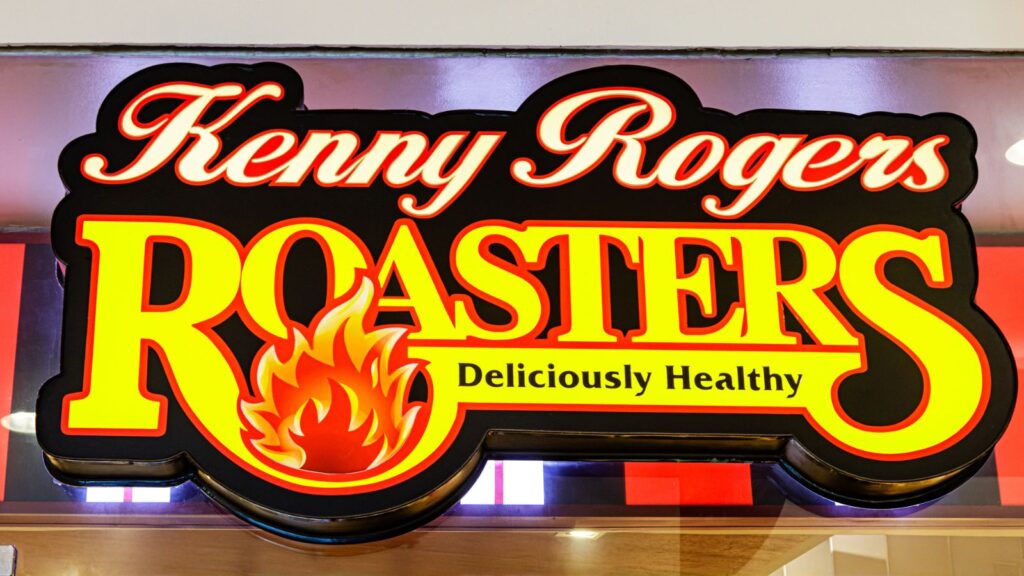 Kenny Rogers ROASTERS restaurant sign with a flame graphic and the slogan “Deliciously Healthy” in yellow and red.