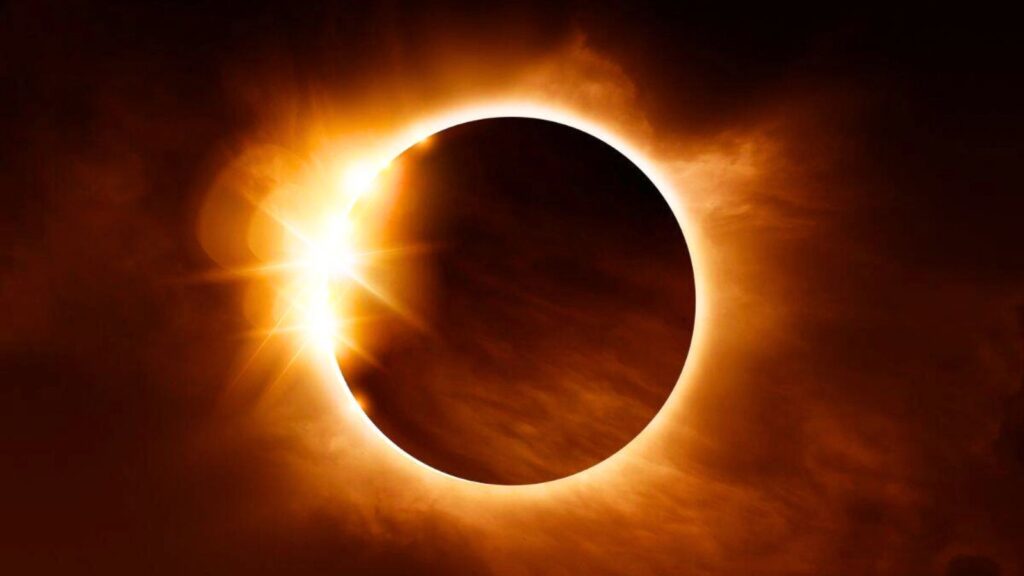 A solar eclipse with the moon covering most of the sun, leaving a bright corona and a burst of sunlight visible at the edge.