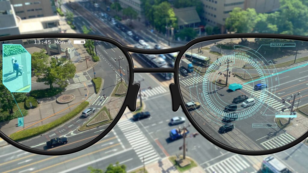 View through smart glasses showing augmented reality overlays, including a person highlight, clock, and interface elements, above a busy city street intersection with cars and pedestrians. The smart glasses seamlessly integrate digital information into the urban environment, enhancing situational awareness for the wearer.