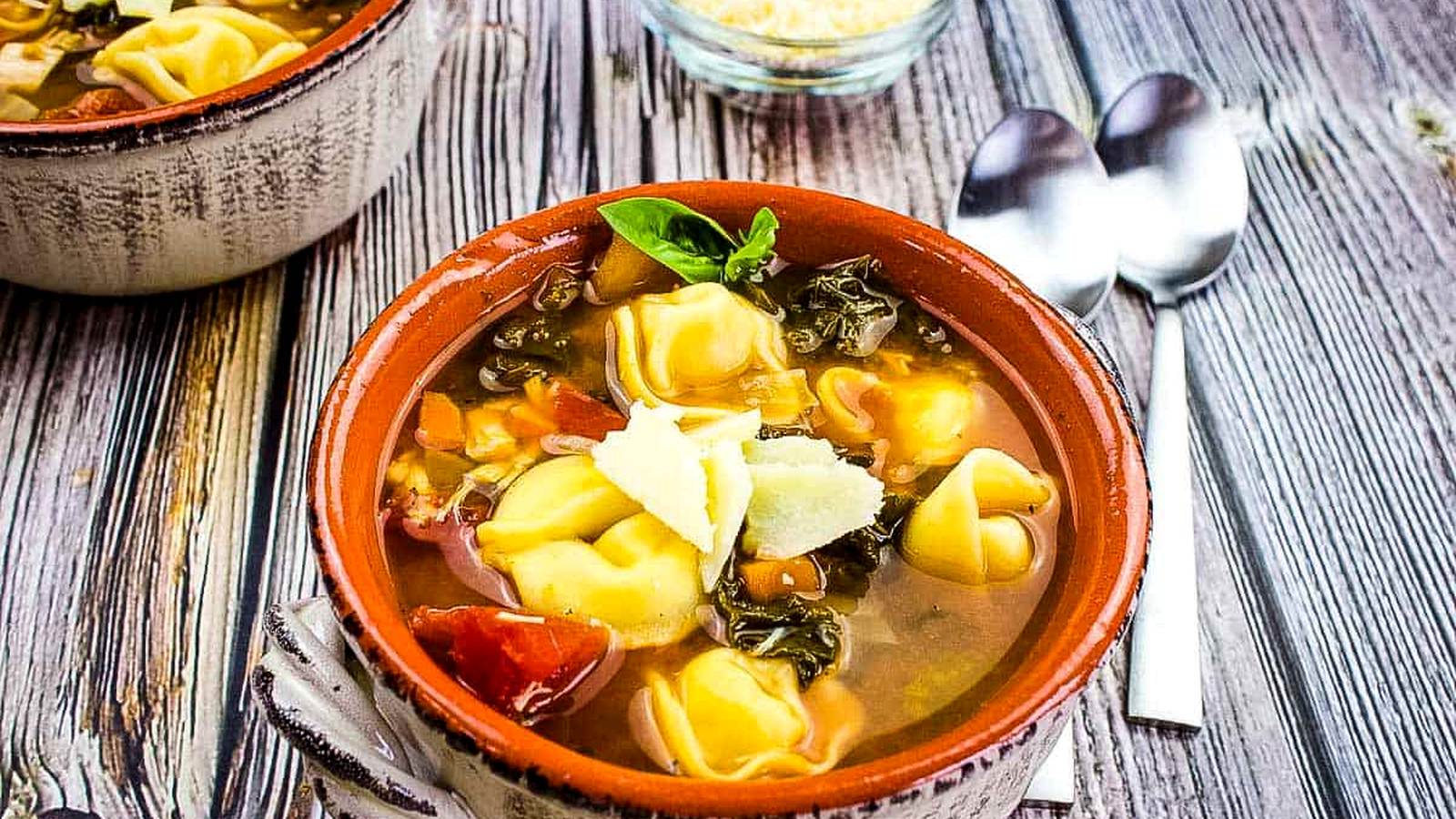 Tortellini Soup with Kale & Chicken in a bowl on a wooden table.