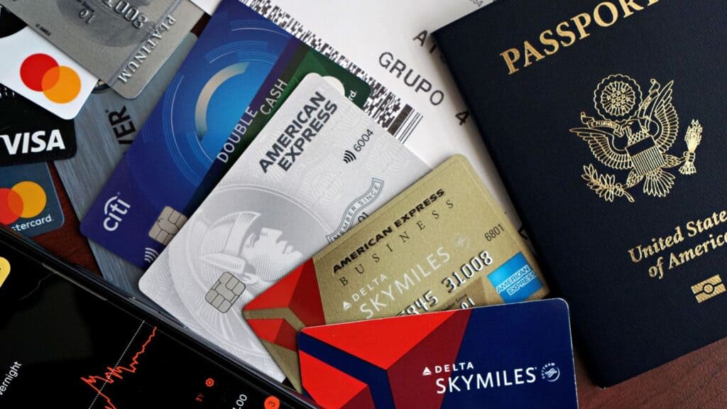 A U.S. passport, several credit cards, a Delta SkyMiles card, and travel documents&mdash;alongside a printout of airline change and cancellation rules&mdash;are spread out on a surface.