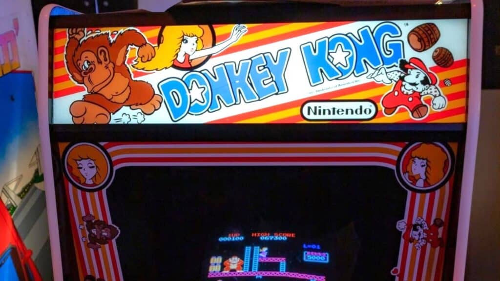 An arcade machine displays Donkey Kong artwork with characters and vibrant colors; the game screen below shows classic gameplay reminiscent of 80s arcade games.