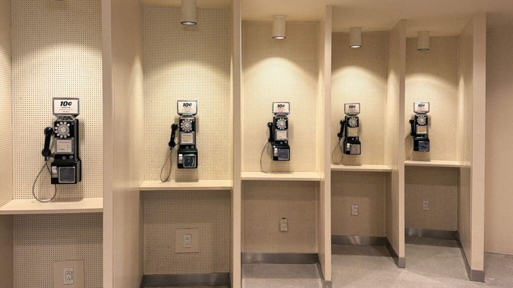 Four vintage rotary payphones in separate beige alcoves, each with a sign indicating a cost of 10 cents per call—a nostalgic reminder of the payphone booth designs America left behind.