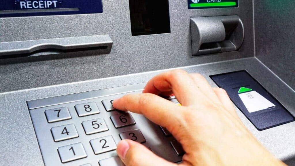 A person&rsquo;s hand pressing a button on an ATM keypad after their debit card was declined abroad.