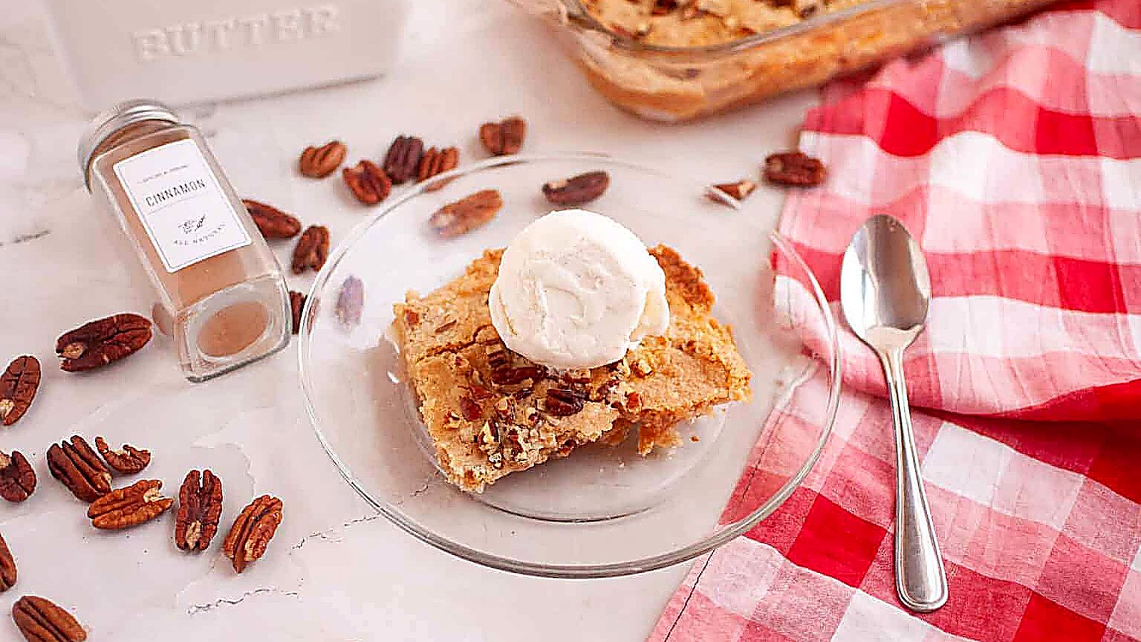 A square of Apple Dump Cake topped with a scoop of vanilla ice cream on a clear plate.