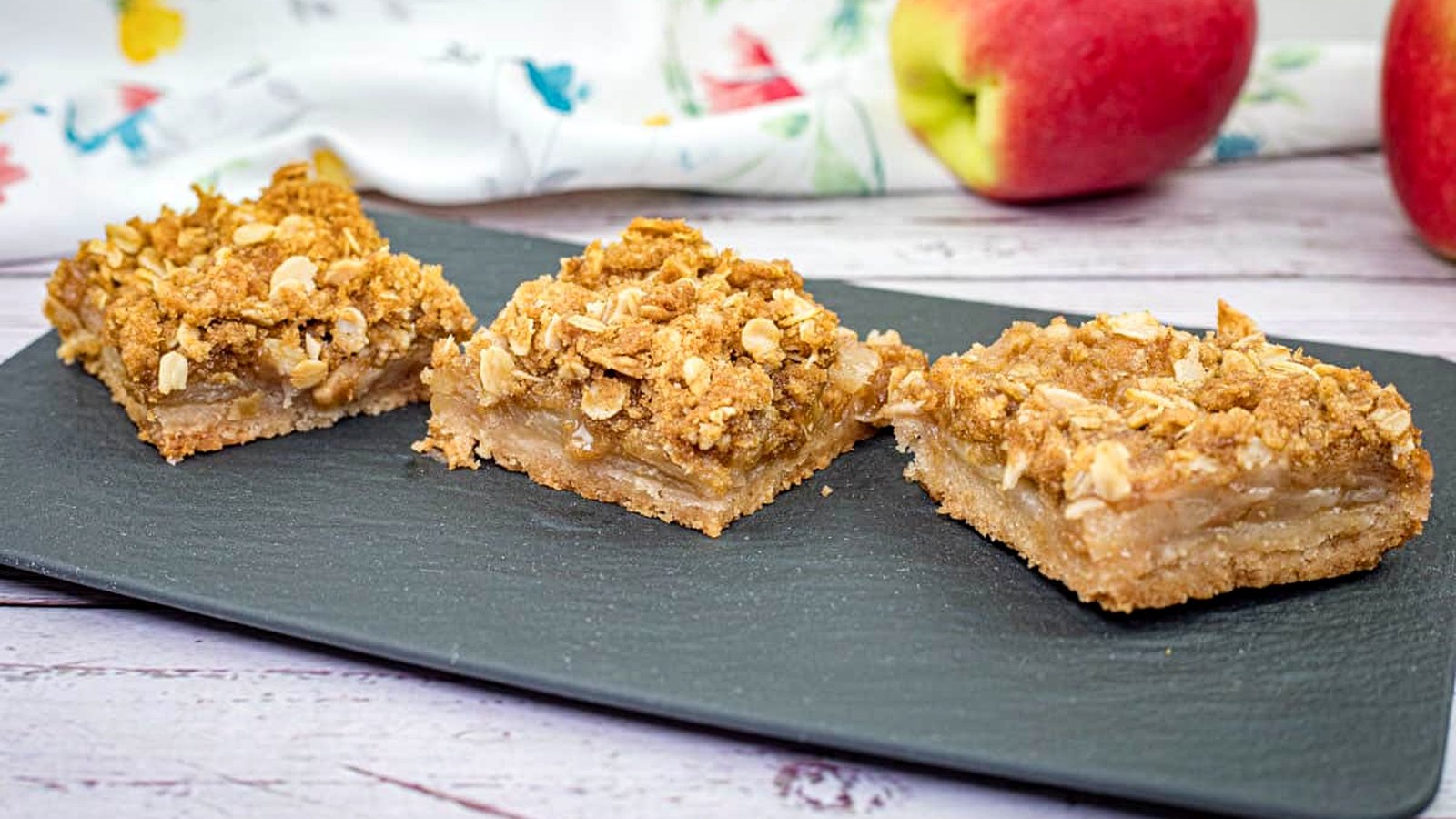 Three pieces of Dutch Apple Pie Squares on a black slate plate.