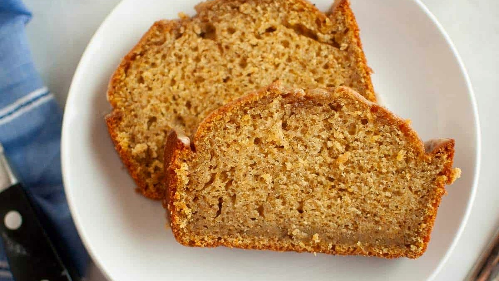 Two slices of Butternut Squash Loaf with Spiced Icing are placed on a white plate, showing a moist and dense texture with a golden-brown crust.