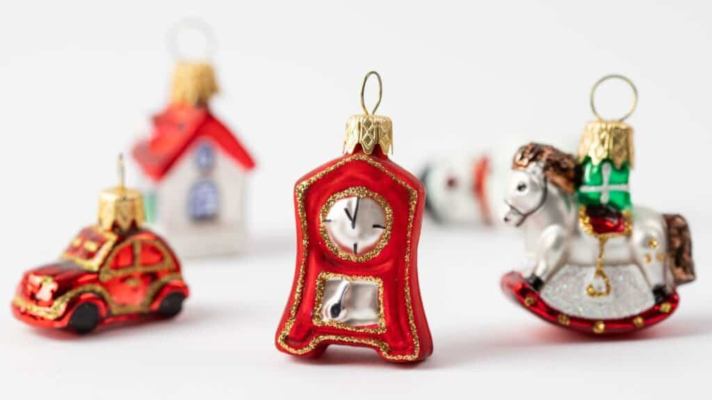 Four glass Christmas ornaments shaped like a car, a house, a grandfather clock, and a rocking horse—classic five and dime staples—displayed on a white background.