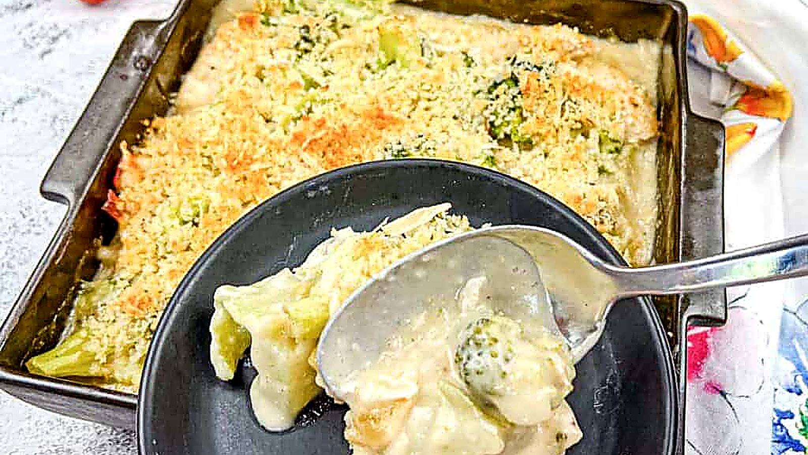 A serving of Turkey Divan from a baking dish onto a black plate.