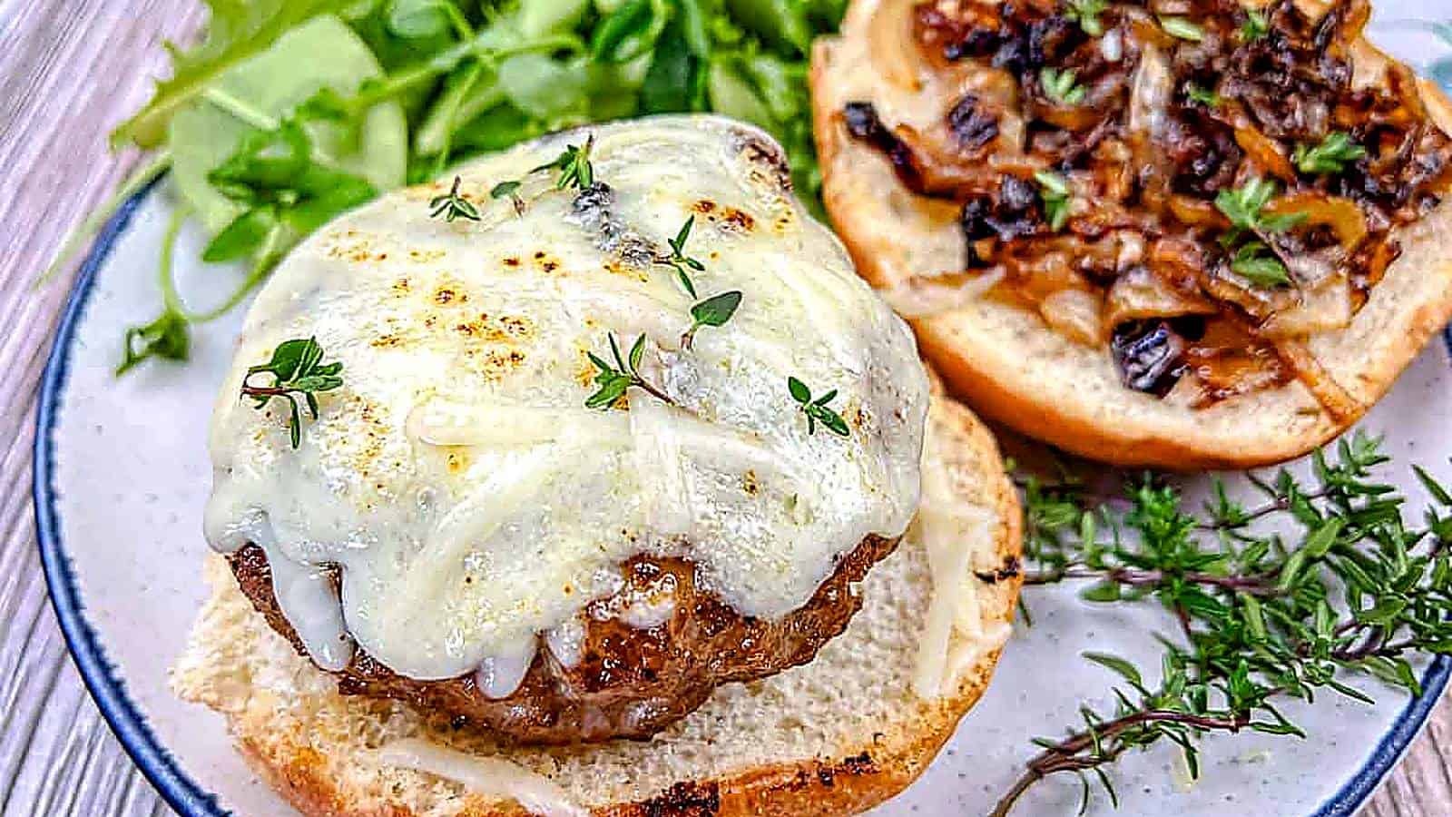 Close-up shot of Grilled French Onion Pork Burgers on a Ninja Woodfire Outdoor Grill topped with cheesy onion on a plate.