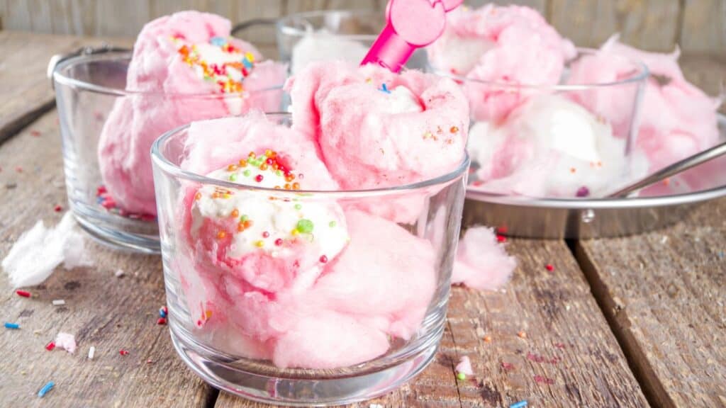 Glass bowls with pink cotton candy and white ice cream topped with colorful sprinkles, placed on a wooden surface&mdash;these whimsical treats wouldn&rsquo;t be out of place among the standout stadium foods at NFL games.