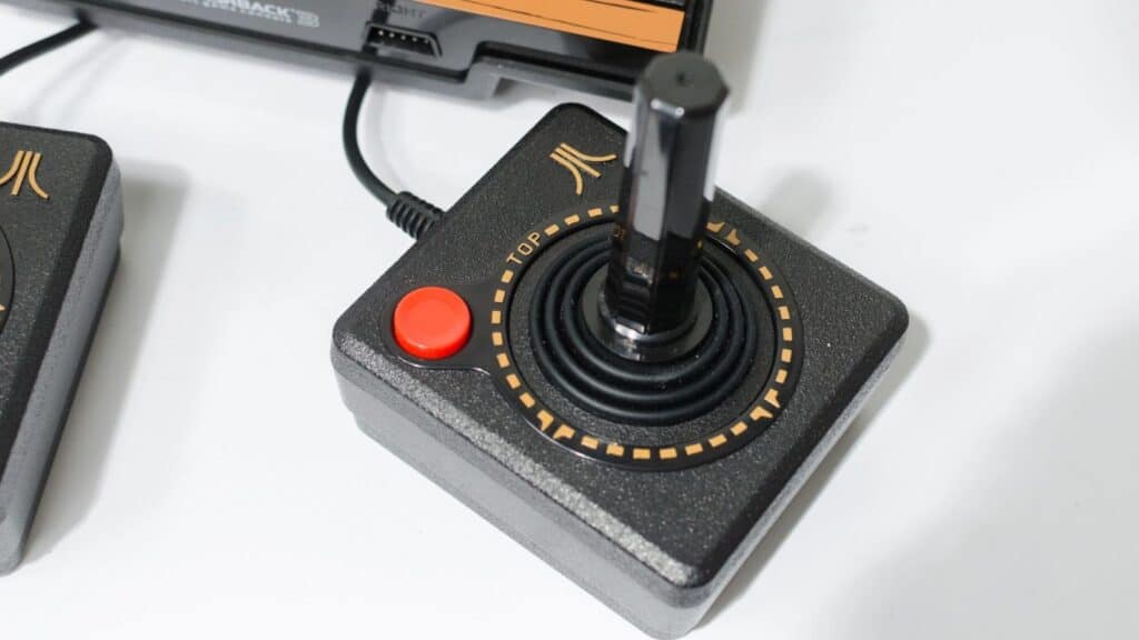 Close-up of a classic Atari joystick controller with a single red button and black stick, connected to a gaming console—evoking nostalgic Atari and early Nintendo memories for retro gaming enthusiasts.