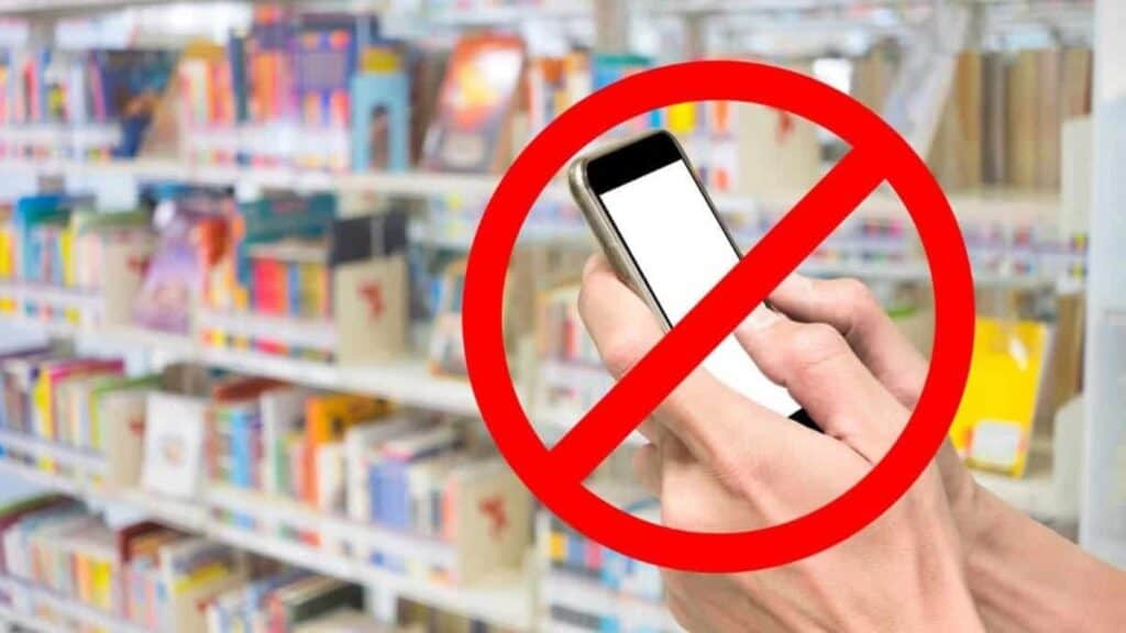 A person holding a smartphone in front of store shelves, with a red prohibition symbol over the phone—emphasizing no phone use allowed, perhaps as a reminder for those whose phone stops working or are considering how eSIMs help in such scenarios.