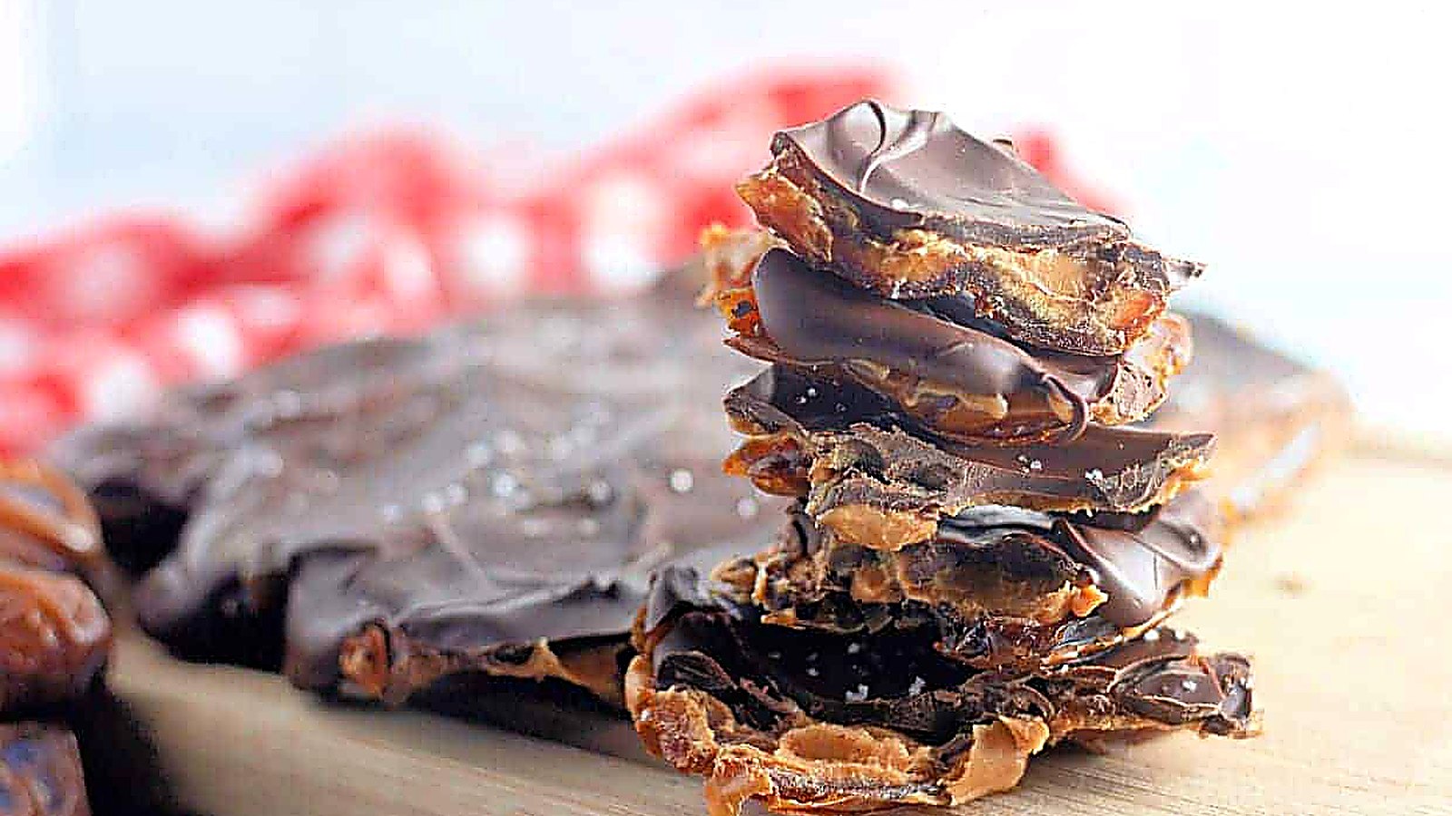 A stack of Peanut Butter and Date Chocolate Bark pieces sits on a wooden board.