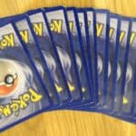 A fan of Pokémon trading cards is showing several cards face down, spread out in a fan shape on a wooden surface—a nostalgic nod to playground fads that ruled recess.