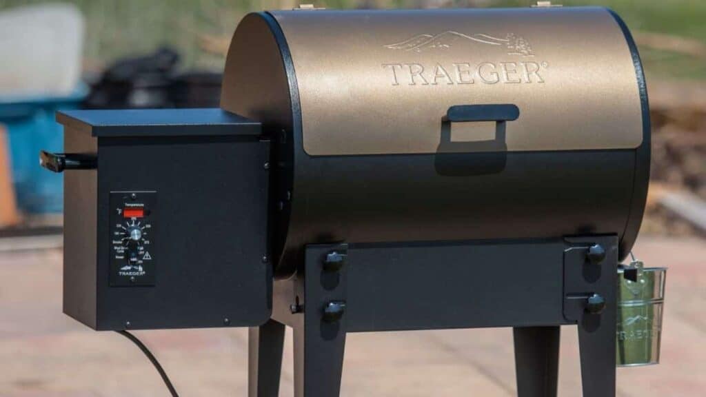A Traeger wood pellet grill with a control panel on the left side, set outdoors on a patio, showcasing tailgating gear in a luxury category.