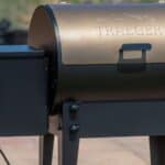 A Traeger wood pellet grill with a control panel on the left side, set outdoors on a patio, showcasing tailgating gear in a luxury category.