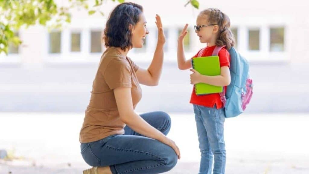 An adult and a child wearing a backpack and holding a notebook give each other a high five outdoors, with a building in the background, evoking memories of &rsquo;80s and &rsquo;90s school supplies.