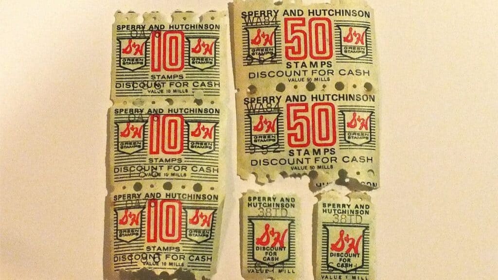 Six vintage trading S&H Green Stamps by Sperry and Hutchinson, four marked “10 STAMPS” and two marked “50 STAMPS,” are arranged on a plain surface.