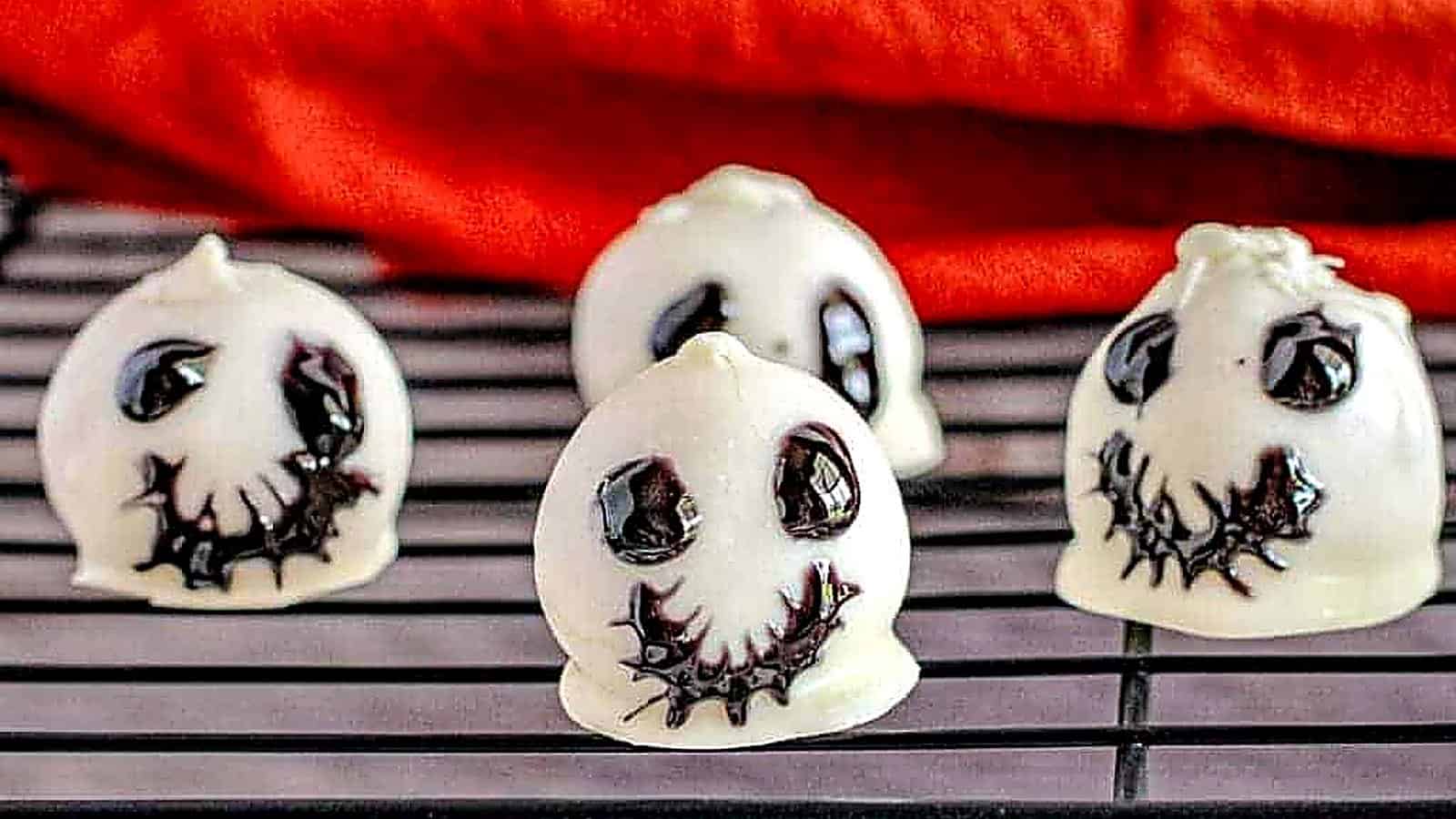 Four pieces of Skeleton Oreo Cookie Balls on a rack.