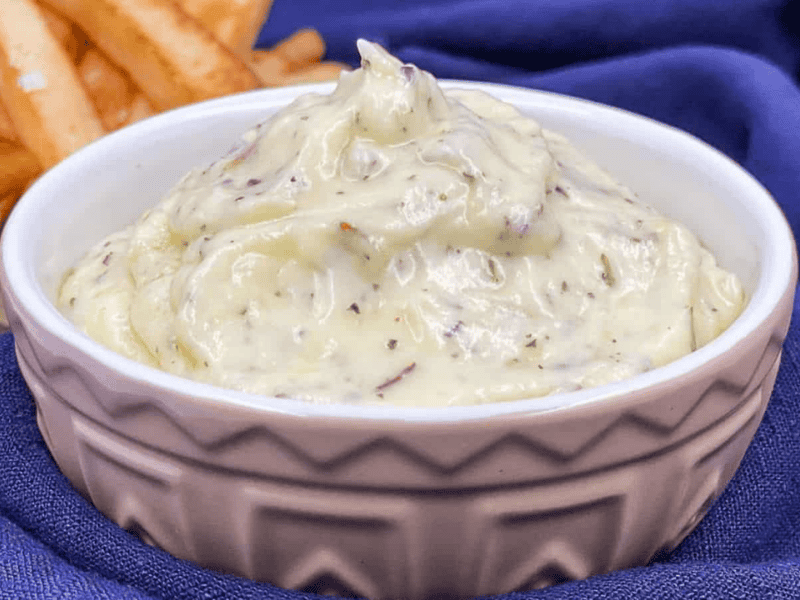 Garlic dip in a serving bowl with fries by it.