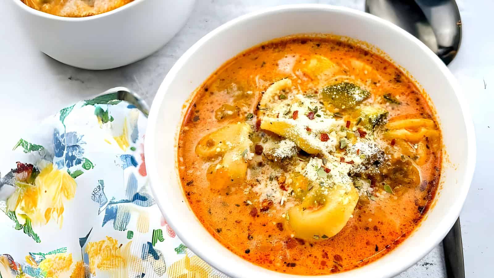 Tortellini Soup with Sausage in a white bowl.