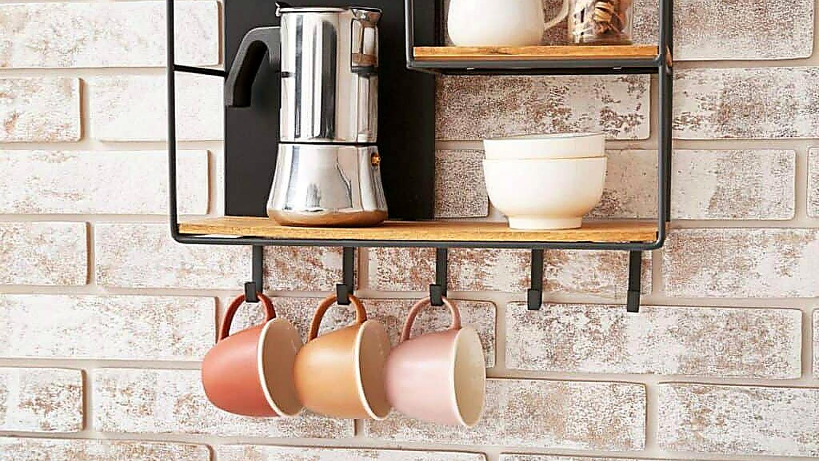 A metal shelf holds a stovetop coffee maker, two bowls, and three ceramic mugs hanging below, all against a light brick wall—an inviting setup perfect for those seeking stylish coffee bar ideas.