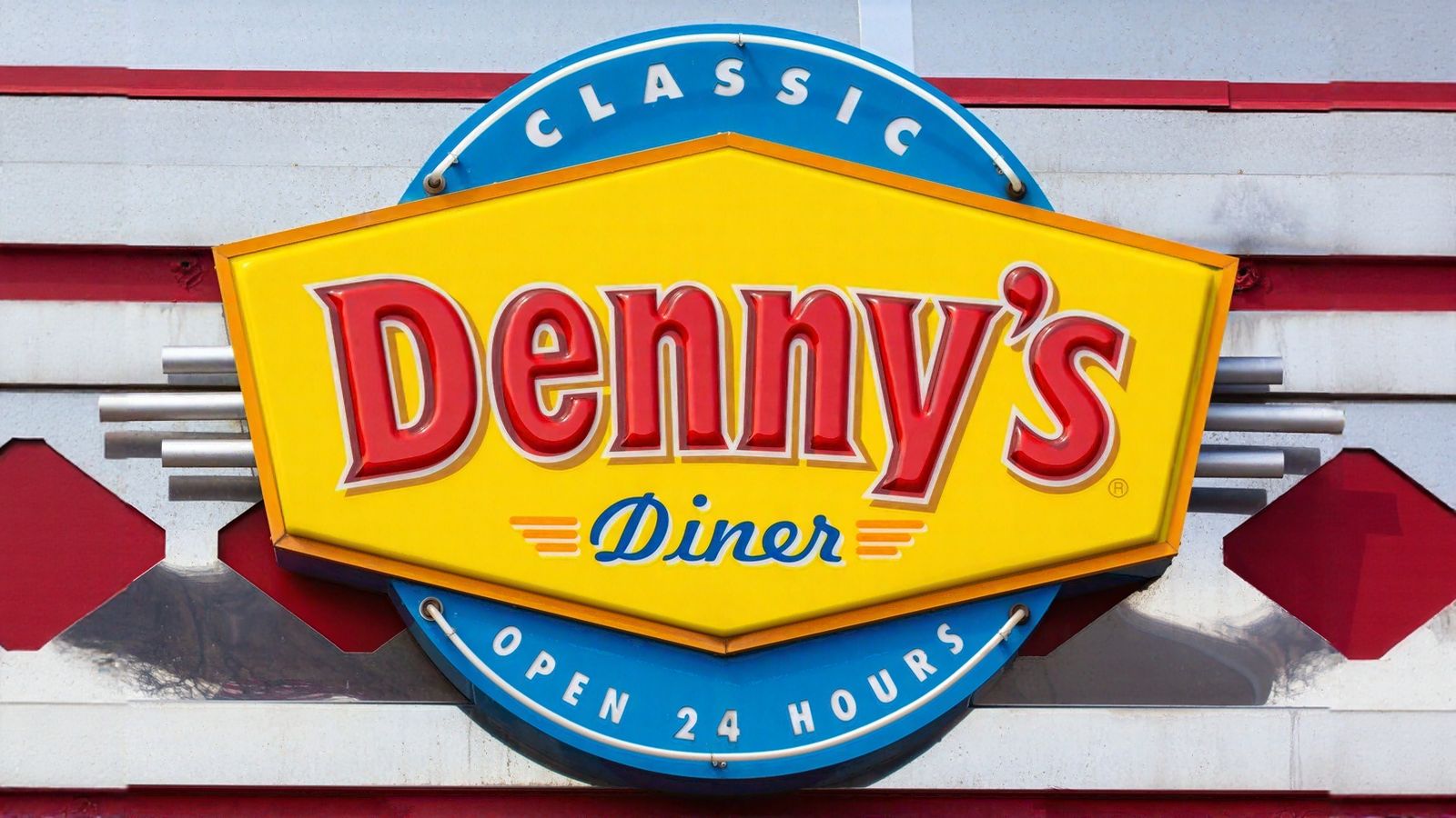 A Denny’s Diner sign with yellow, red, and blue colors reads “Classic Denny’s Diner Open 24 Hours,” mounted on a building exterior.