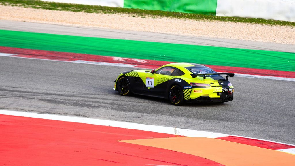 A yellow and black race car with the number 111 drives on a racetrack with colorful red, green, and white sections.